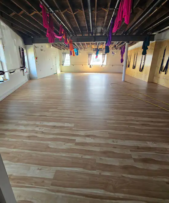 The same studio with its finished plank floor under aerial silks