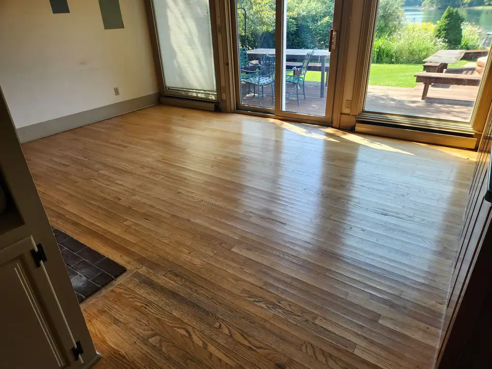 Oak floor in a sunny room with sliding doors open to a patio