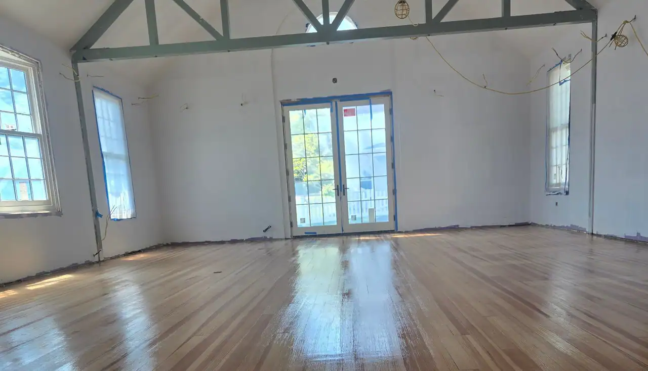 A big hall with a freshly finished pine floor shining under a timber truss