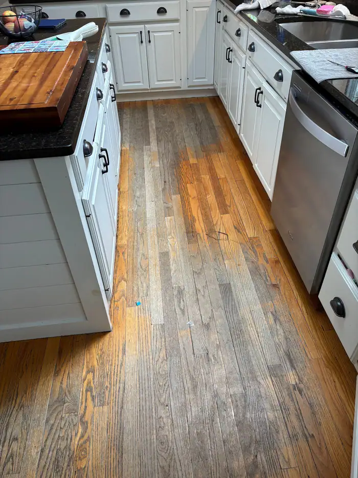 Galley kitchen with rustic plank flooring and white cabinets