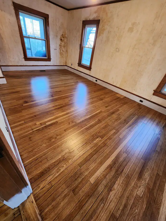 Oak floor refinished to a deep gloss in a sunny room with old plaster walls