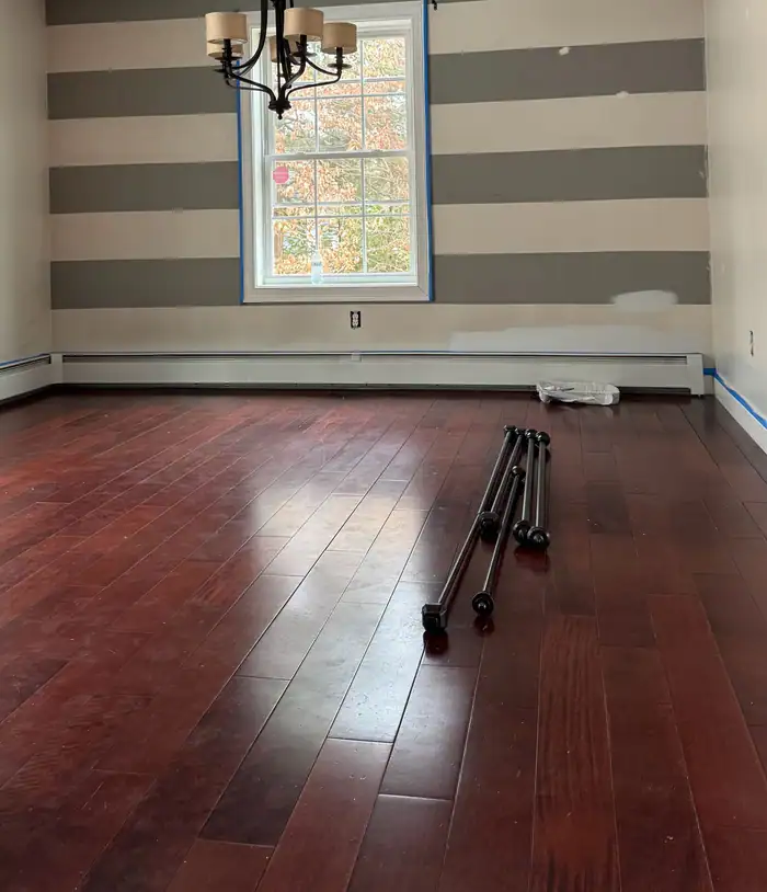 Dark-stained floor in a room with a striped wall and chandelier