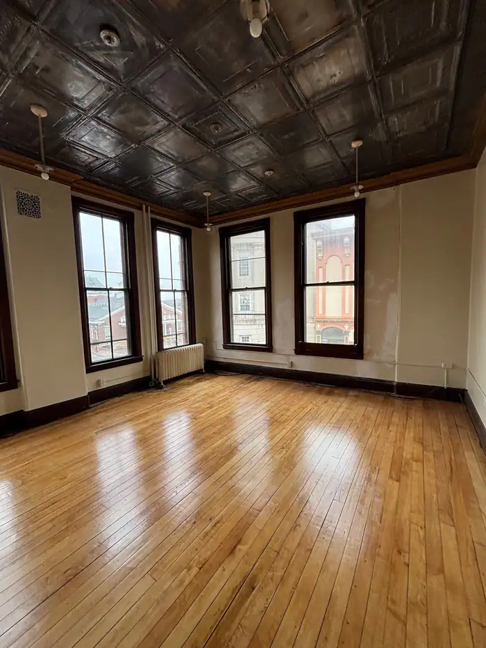 Glossy oak floor refinished under a pressed-tin ceiling and tall windows