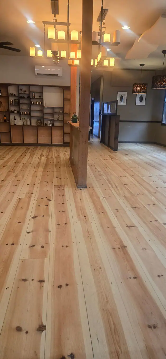 Wide pine floor in an open room with a center post and pendant lights