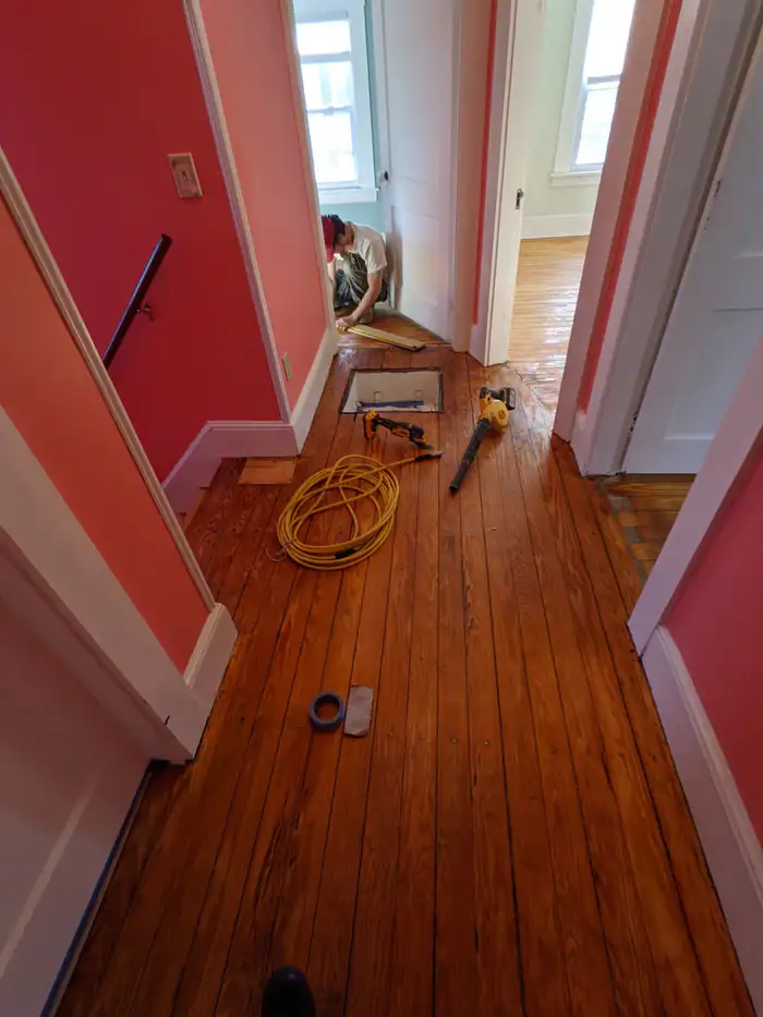 Old pine hallway floor mid-repair with tools on the boards