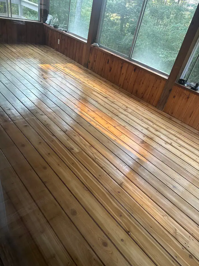 Wide pine boards refinished in a sunroom lined with windows