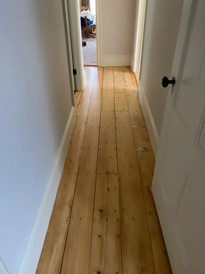 Narrow pine-floored hallway with white doors