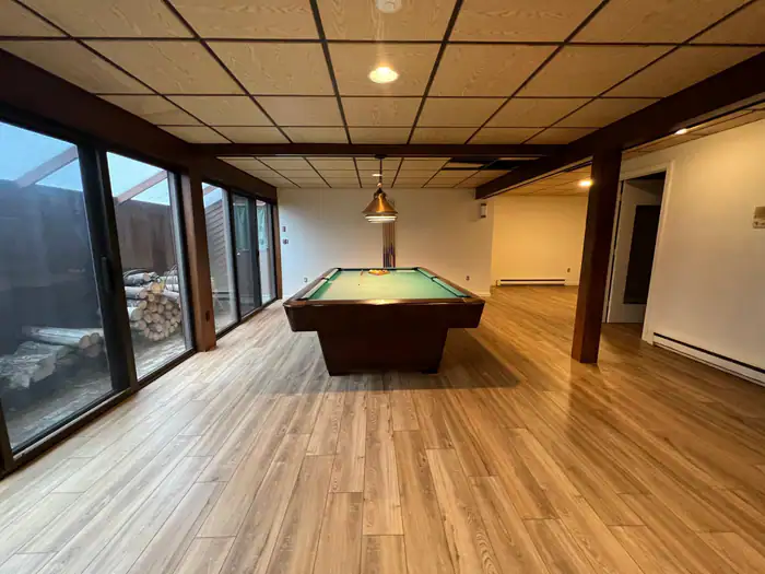 Vinyl plank floor in a finished basement with a pool table and sliding doors