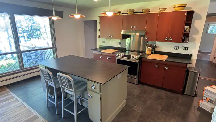 Kitchen with an island and a dark floor beside big windows