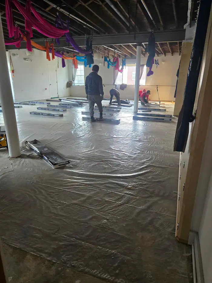 Crew installing new plank flooring across a studio