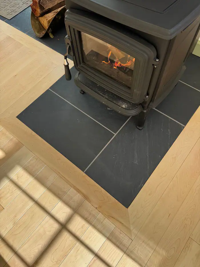 Wood stove on a slate tile hearth set into a light oak floor