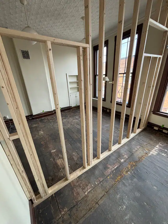 Old dark floorboards exposed behind new wall framing