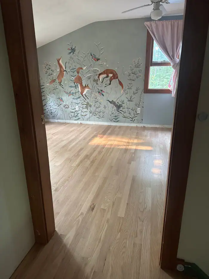 Natural oak floor in a room with a painted mural wall