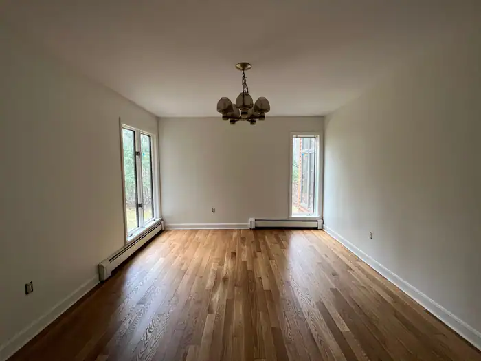 Oak floor in an empty dining room with a brass chandelier