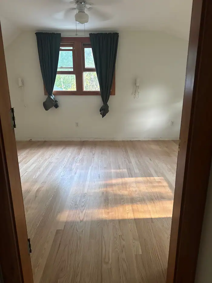 Natural oak floor in a room with dark green curtains