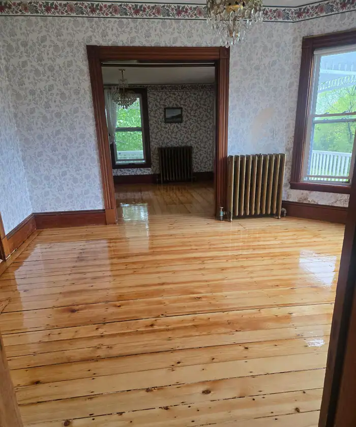 Wide pine boards refinished in a room with radiators and floral wallpaper