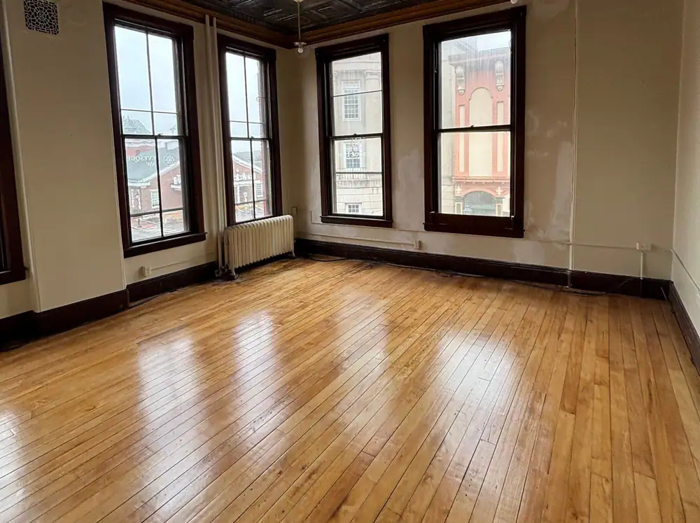 Glossy oak floor under a pressed-tin ceiling and tall windows
