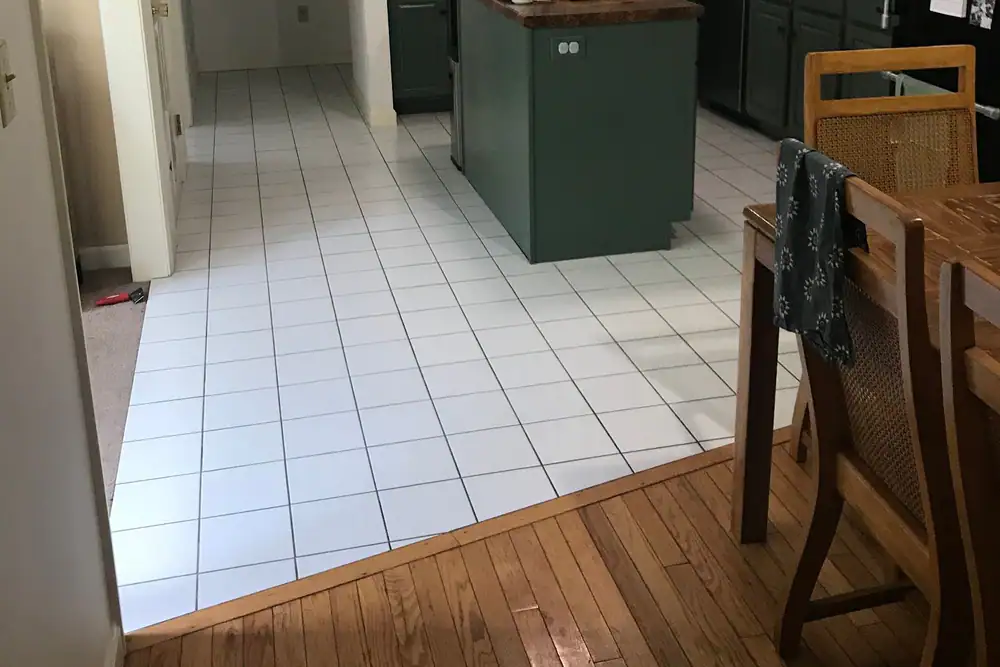 White tile kitchen floor meeting an oak floor at a clean edge