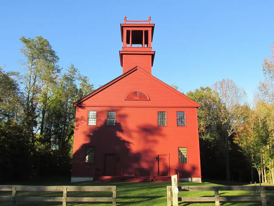 The Old Red Church at Standish Corner, Maine, under a blue sky